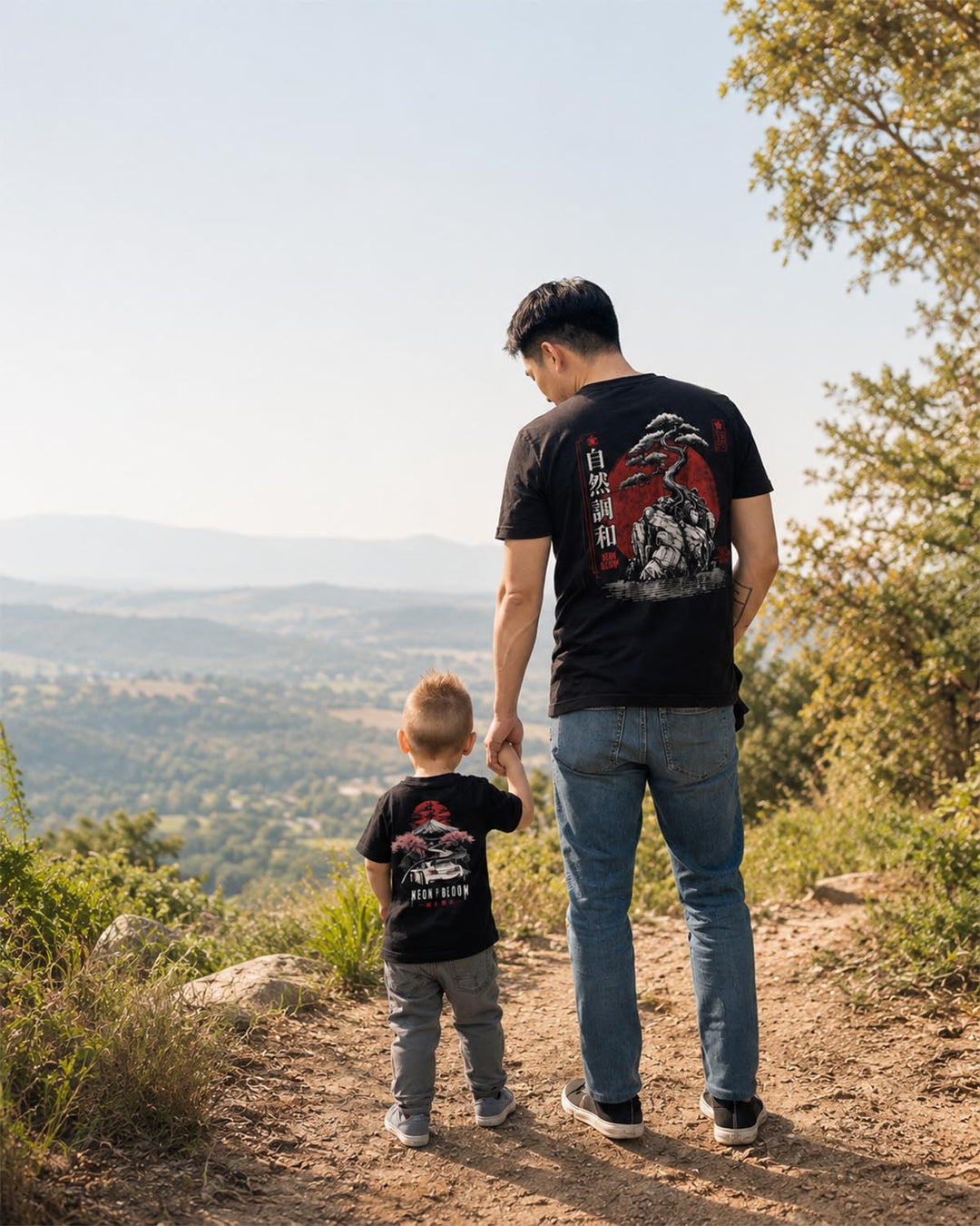 Man and child walking on a trail with scenic view wearing Japanese graphic tees.