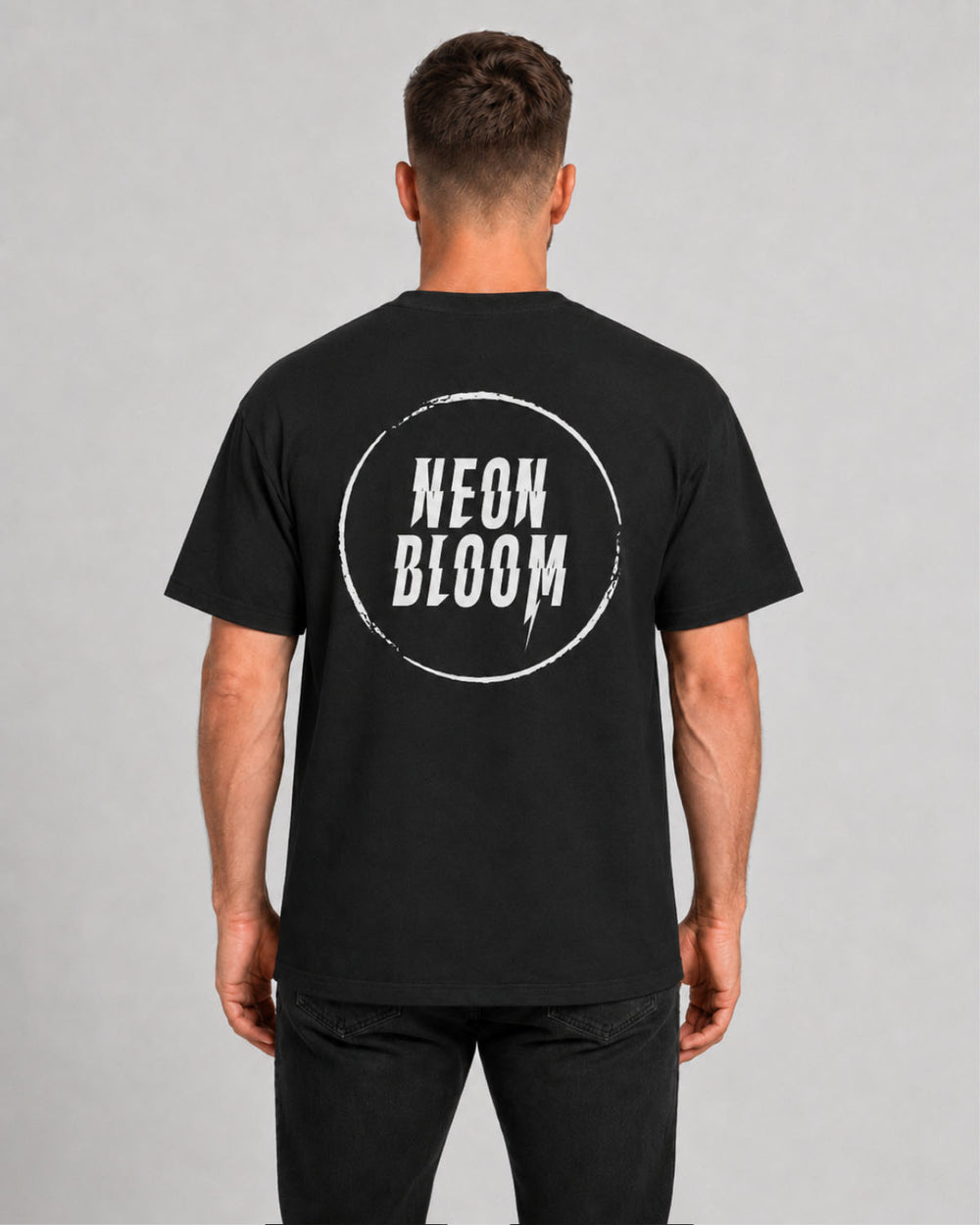 Person wearing a black t-shirt with 'NEON BLOOM' logo on the back against a gray background