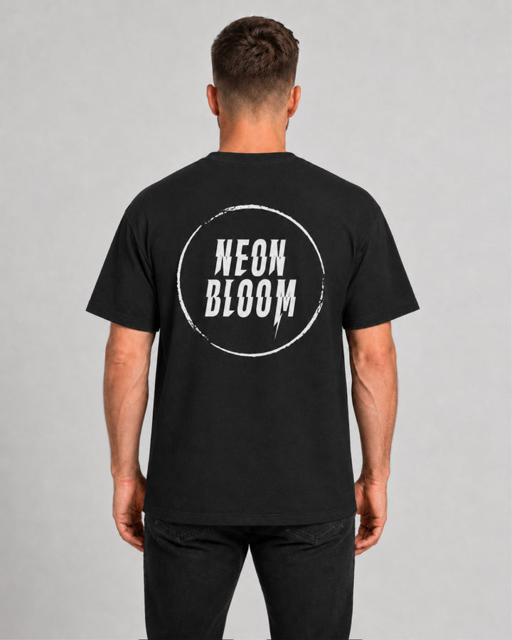 Person wearing a black t-shirt with 'NEON BLOOM' logo on the back against a gray background