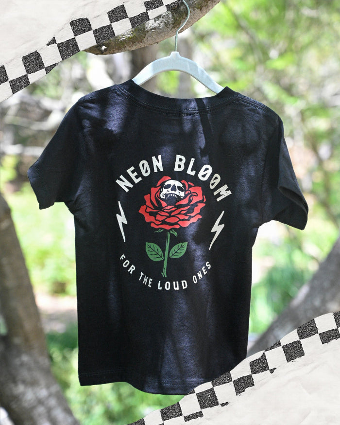 Black t-shirt with a red rose graphic and text on a hanger against a natural background