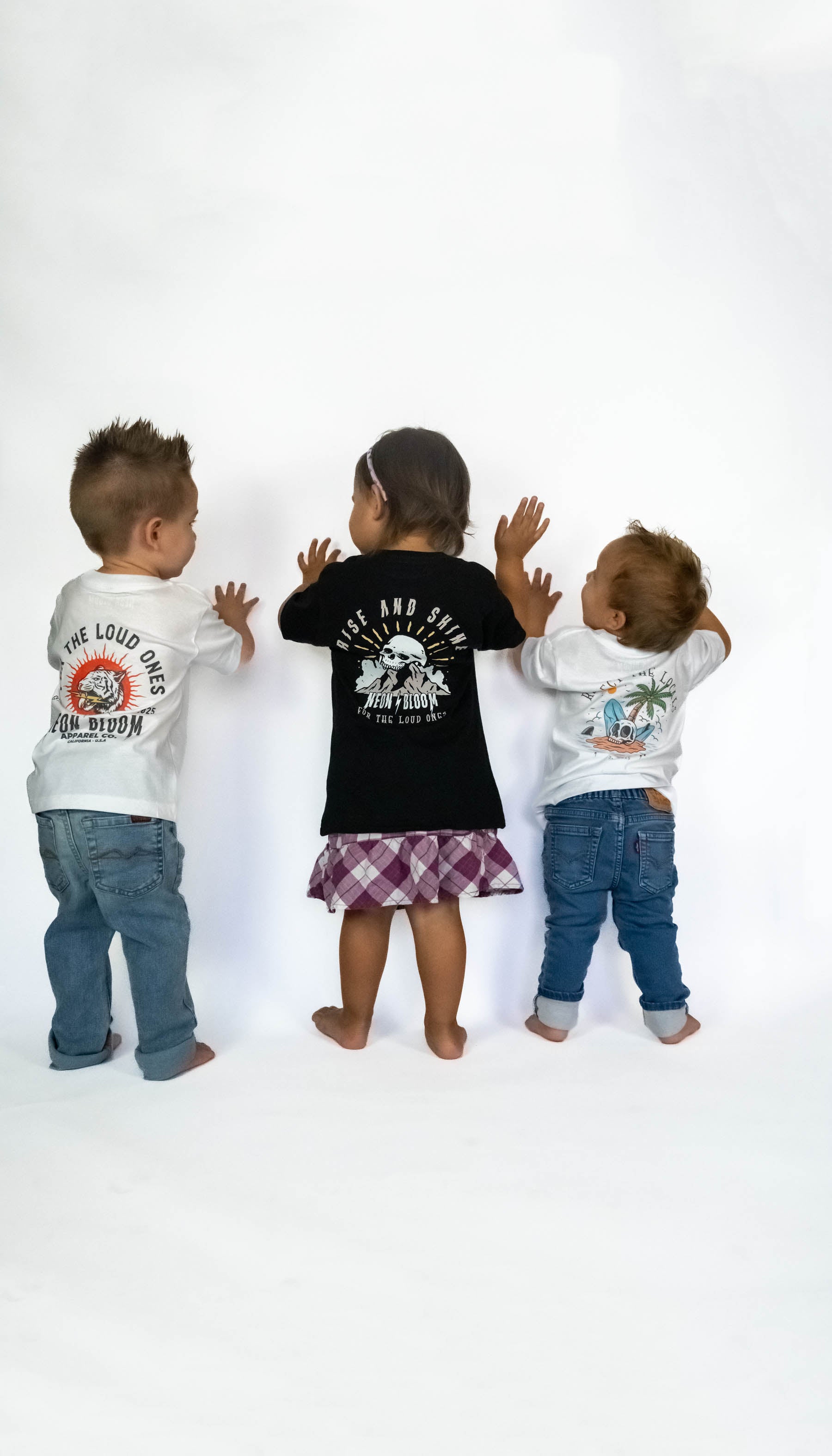 Three children wearing graphic t-shirts on a white background